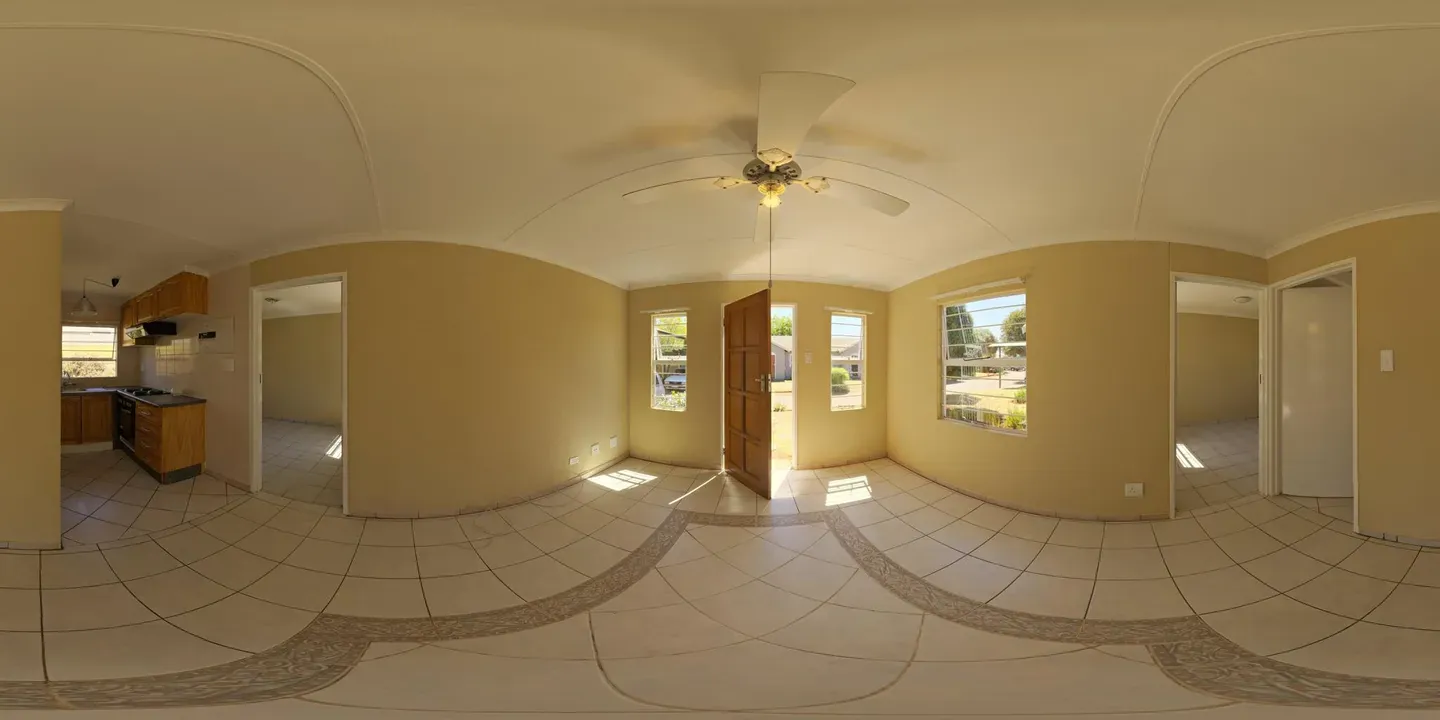 A 360° panorama of a small empty house with a kitchen corner, open front door and windows